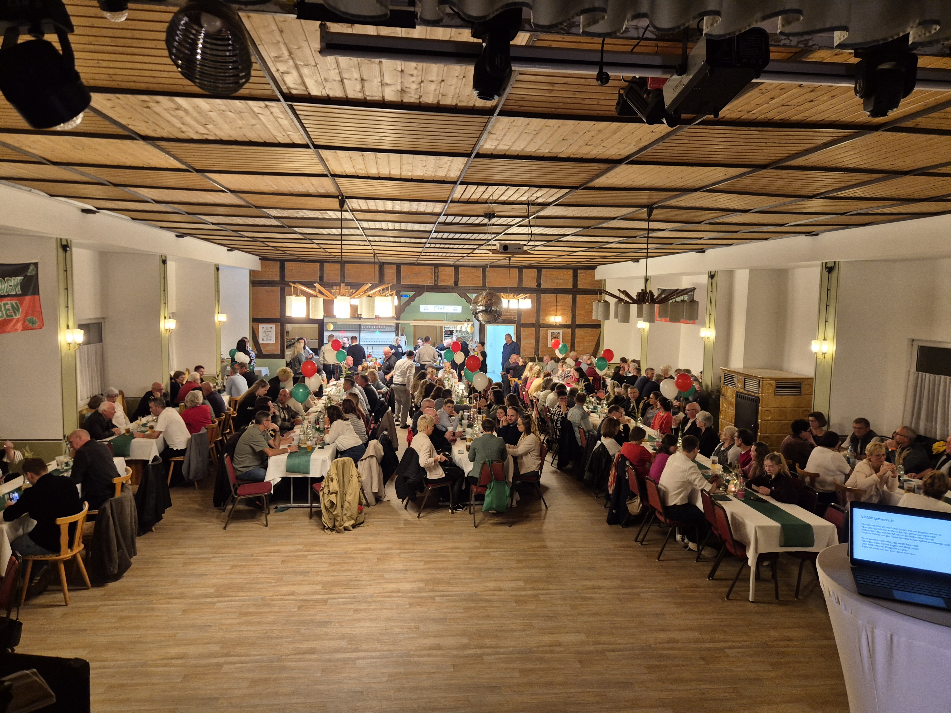 Blick in den Saal der Gaststätte Kersten beim Sportlerball: gedeckte Tischreihen und freie Fläche vor der Bühne.